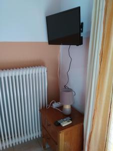 uma televisão numa parede por cima de uma mesa com um candeeiro em Valta's Room em Paleros