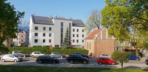 Un estacionamiento con autos estacionados frente a un edificio. en Apartament w centrum Olsztyna - Grunwaldzka, en Olsztyn