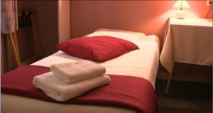 a bed with two towels and a red pillow at Hotel Anvers in De Panne