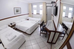 a hotel room with two beds and a table and chairs at Hotel das Palmeiras in Teófilo Otoni