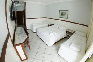 a small room with two beds and a couch at Hotel das Palmeiras in Teófilo Otoni