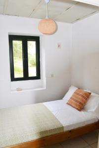 a white bedroom with a bed and a window at LIOTRIVI Olive Press in Volimes