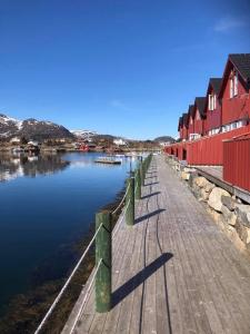 a dock with red buildings next to a body of water at Ballstad Brygge Rorbu in Ballstad