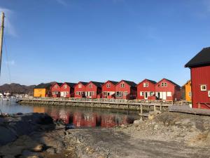 una fila di case rosse vicino a un corpo d'acqua di Ballstad Brygge Rorbu a Ballstad