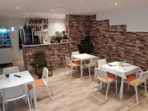 a restaurant with white tables and chairs and a brick wall at Casa Gabriel in Picassent