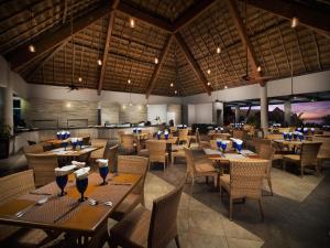 a restaurant with wooden tables and chairs and a kitchen at El Cid La Ceiba Beach in Cozumel