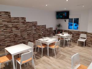 a restaurant with white tables and chairs and a brick wall at Casa Gabriel in Picassent