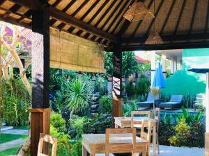 eine Terrasse mit Tischen und Stühlen im Garten in der Unterkunft D'Waktu in House in Nusa Lembongan