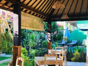 a patio with tables and chairs in a garden at D'Waktu in House in Nusa Lembongan