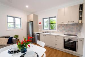 a kitchen with white cabinets and a table with flowers on it at Island Cottages in Nelly Bay