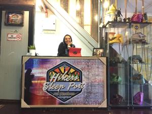a woman standing at a podium with a laptop at Hikers Sleep Port Guesthouse in Cameron Highlands