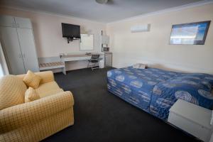 a hotel room with a bed, couch and a television at Copper City Motel in Cobar