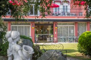 une statue en face d'un bâtiment avec des tables et des chaises dans l'établissement Best Western Beauséjour, à Lourdes