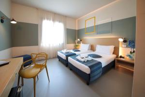 Habitación de hotel con 2 camas y escritorio en Best Western Hotel Cristallo Mantova, en Virgilio