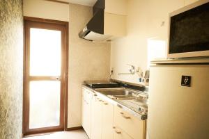 a small kitchen with a sink and a refrigerator at Nagomi TABI-NE in Kanazawa
