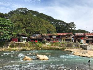 a river with a group of houses in the background at Villa Paradise - Bukit Lawang in Bukit Lawang