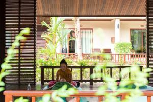 a woman sitting on a bench in front of a house at Khaolak Bayfront Resort in Khao Lak