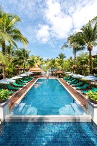uma piscina com espreguiçadeiras e palmeiras em Khaolak Bayfront Resort em Khao Lak