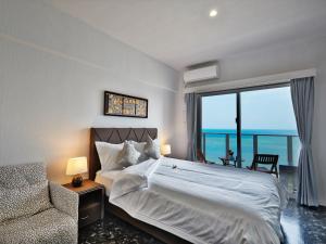 a bedroom with a bed and a chair and a window at Beach Front Tower Mihama by DSH in Chatan