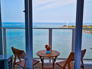 a room with a table and chairs and a view of the ocean at Beach Front Tower Mihama by DSH in Chatan