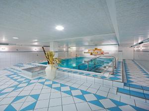 a large swimming pool in a large room with a tile floor at Art Hotel Aachen in Aachen