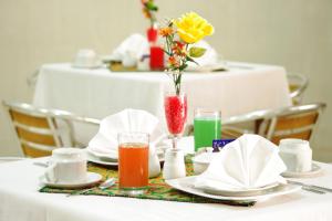 a table with plates and drinks and a vase of flowers at Del Castillo Plaza Hotel Pucallpa in Pucallpa