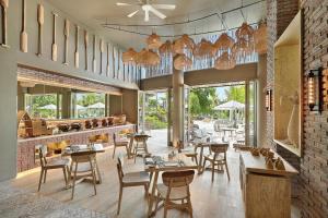 a restaurant with wooden tables and chairs and windows at Cross Bali Breakers - formerly X2 Bali Breakers in Jimbaran