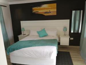 1 dormitorio con cama blanca y almohada azul en Double L Guest Lodge Palapye en Palapye