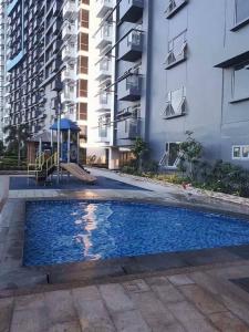 a swimming pool with a playground in front of some buildings at Cubao ManhattanHeights Unit 7EF Tower B, 1BR in Manila