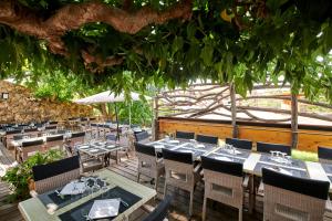 restauracja ze stołami i krzesłami pod drzewem w obiekcie Hôtel restaurant le Ressac w mieście Belvédère-Campomoro