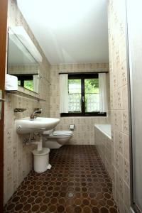 een badkamer met een wastafel, een toilet en een bad bij Lärchenwald 1805 in Leukerbad