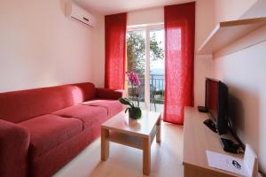 a living room with a red couch and a table at Apartments Amabilis in Selce