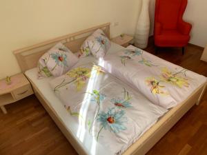 a bed with white sheets with flowers on it at Haus Helga in Lienz