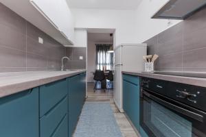 La cuisine est équipée de placards bleus et d'un réfrigérateur. dans l'établissement Apartment Tragurion, à Trogir