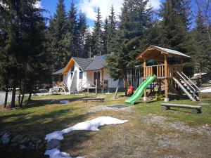 a playground in front of a house with a building at Complex Transalpina Lac in Voineasa