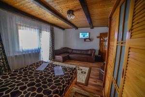 a bedroom with a bed and a couch in a room at Pensiunea Montana Muntele Mic in Muntele Mic