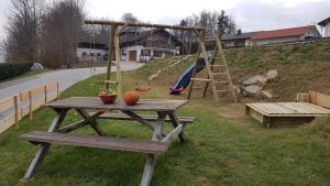 una mesa de picnic de madera con un parque infantil en una colina en Ferienhaus Rachelblick en Kirchberg