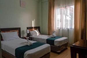 Dos camas en una habitación de hotel con cisnes. en Adams View Hotel en Moalboal