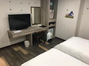 新竹市的住宿－心園生活旅店 Xin Yuan Hotel，客房设有一张桌子、一台电视和一张床
