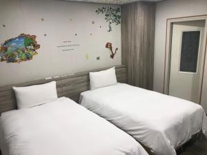 新竹市的住宿－心園生活旅店 Xin Yuan Hotel，两张睡床彼此相邻,位于一个房间里