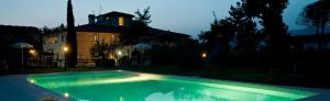 a swimming pool in front of a house at night at Il Pino Bioagricoltura in Terranuova Bracciolini