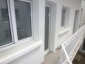 Cet appartement comprend deux fenêtres donnant sur un bâtiment blanc et un balcon. dans l'établissement T3 centre Lourdes, à Lourdes