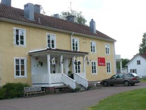 a yellow house with a car parked in front of it at Lönneberga Vandrarhem & Hostel in Lönneberga