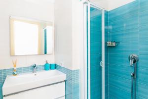 La salle de bains bleue est pourvue d'un lavabo et d'une douche. dans l'établissement EverSun, à Massa Lubrense