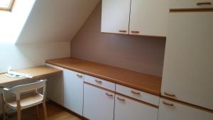 a kitchen with white cabinets and a table and a chair at Altstadtappartements Hartberg in Hartberg