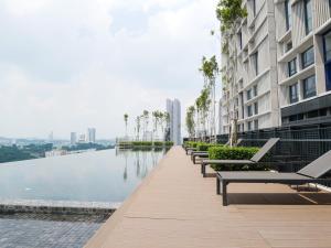 een rij banken naast een waterlichaam bij Tamarind Suites by Elite Stay in Cyberjaya