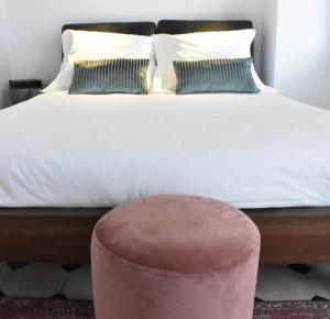 a bedroom with a white bed with a pink stool at Apartamentos Las Naranjas in Jerez de la Frontera +31 photos