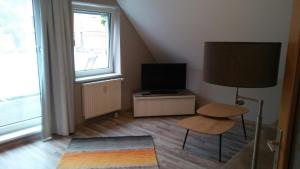 ein Wohnzimmer mit einem TV, einem Tisch und einer Lampe in der Unterkunft Altstadtappartements Hartberg in Hartberg