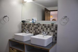 Baño con 2 lavabos y espejo en Kramersdorf Guesthouse, en Swakopmund