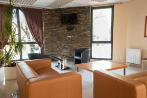 a lobby with chairs and a table and a tv at Hôtel Garabel in Plaisir